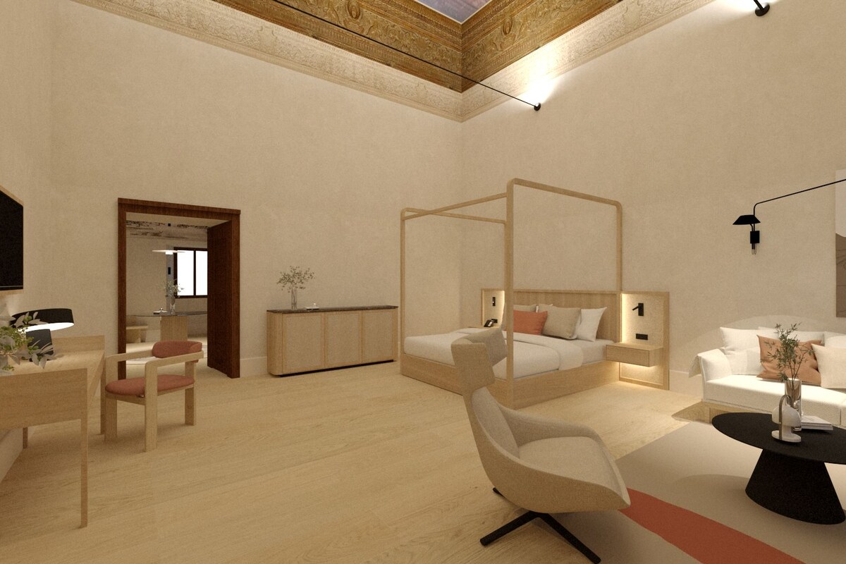 A modern bedroom with a four-poster bed, a sofa, a desk with a chair, and a bedside table.