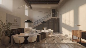 Ein modernes Interieur mit einer Treppe, einer Essecke inklusive Stühle und Tisch sowie einer großen Pflanze.