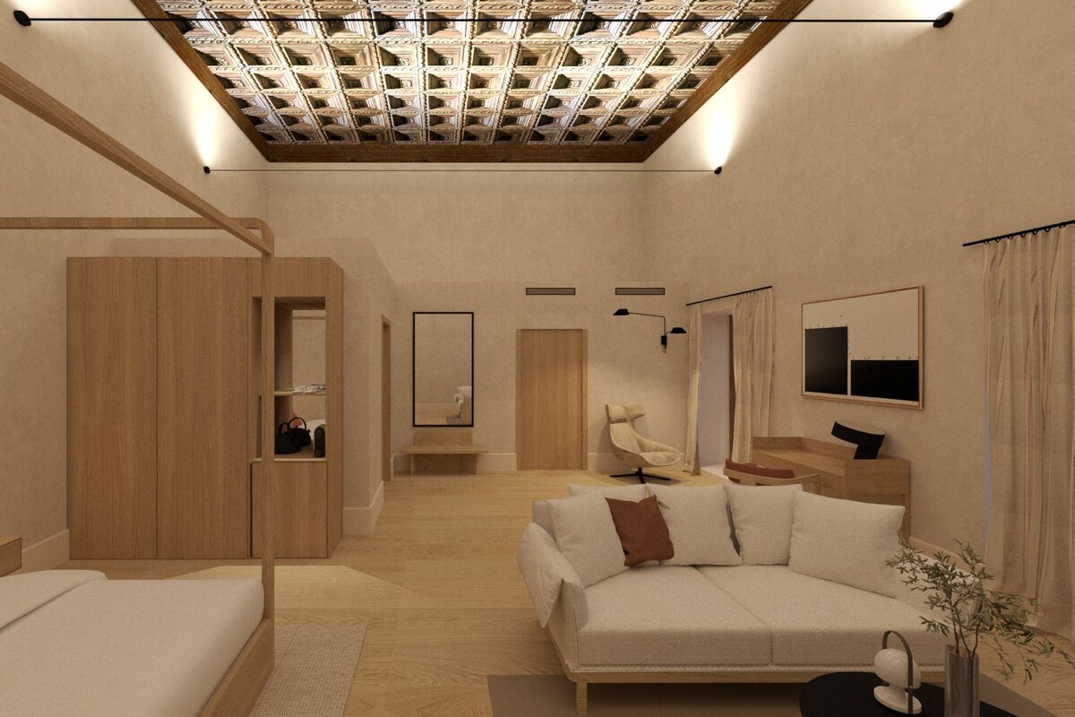 A modern bedroom with a wooden wardrobe, a sofa, a bed, a mirror, and a ceiling with a geometric pattern.