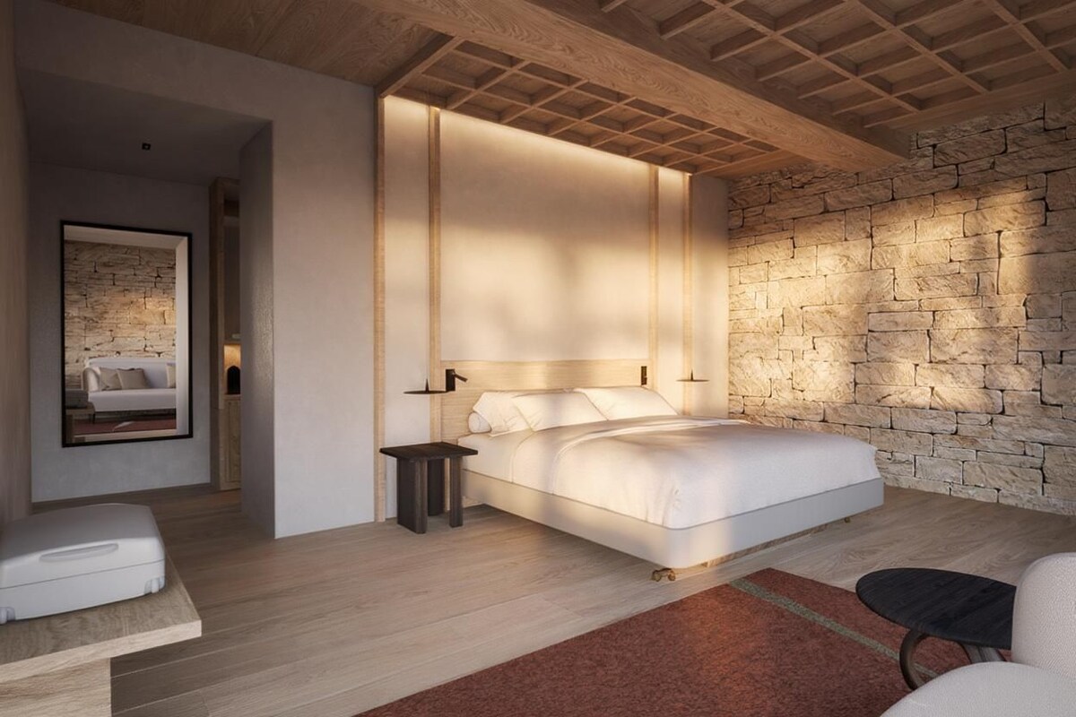 A modern bedroom with a large bed, a stone accent wall, and a minimalist design.