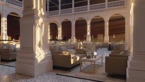 A spacious lobby with multiple seating areas, large columns, and a balcony overlooking the interior.