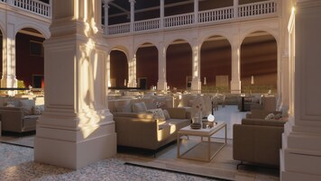 Un vestíbulo amplio con varias zonas de estar, columnas imponentes y un balcón con vistas al interior.