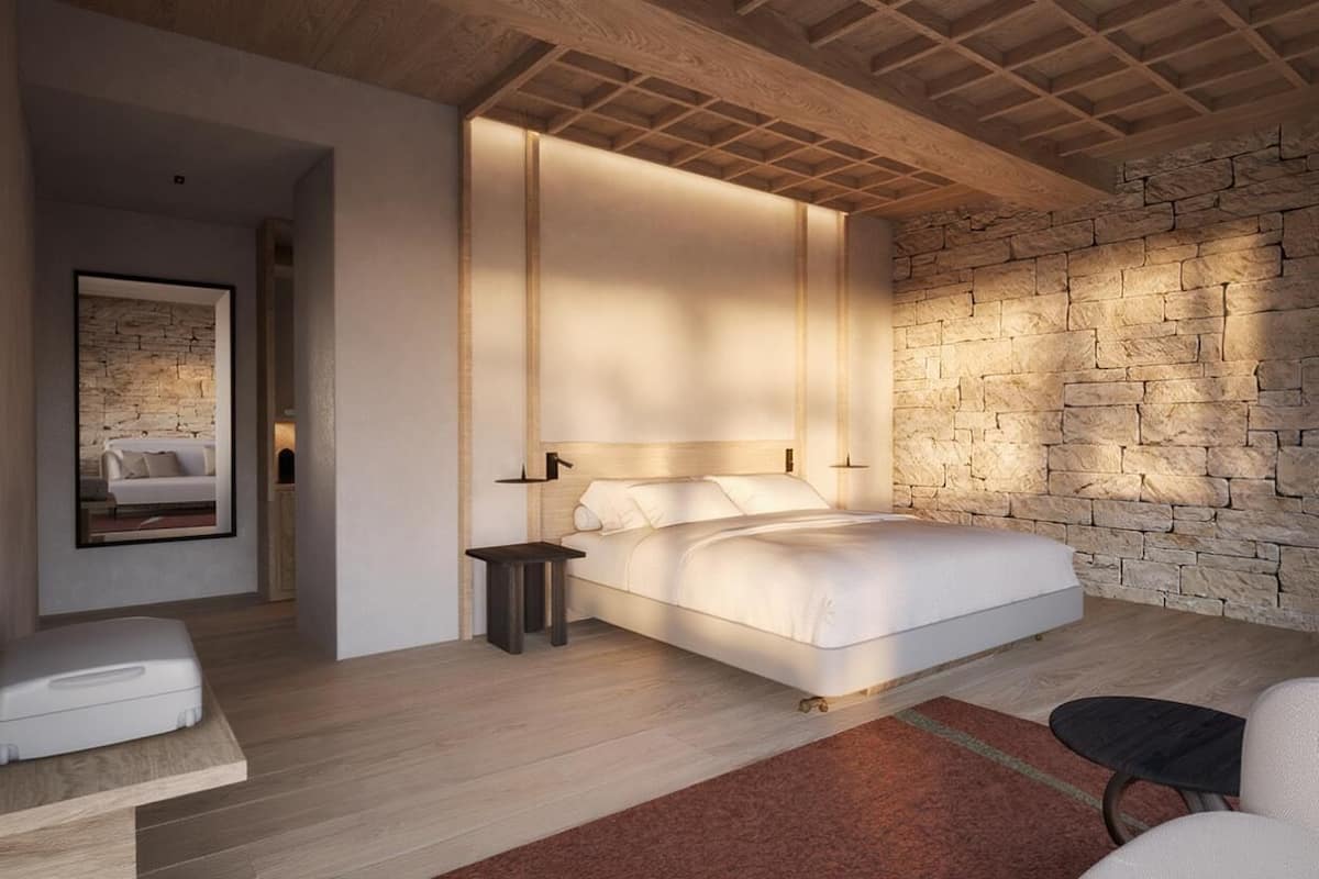 A modern bedroom with a large bed, a stone accent wall, and a minimalist design.