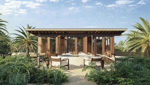 A covered outdoor seating area with a hot tub, surrounded by lush greenery and palm trees.