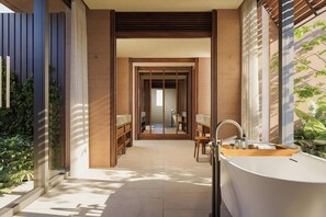 A modern bathroom with a freestanding bathtub, a sink, and a mirror. There is a door leading to another room. - Siari Riviera Nayarit A Ritz Carlton Reserve (Compostela)
