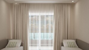 A modern hotel room with two single beds, a glass coffee table, and a large window with sheer curtains. - Laguna Holiday Resort Corfu (Corfu)