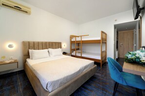 A bedroom with a large bed, a bunk bed, a desk with a chair, and a bedside table with a lamp. - Laguna Holiday Resort Corfu (Corfu)