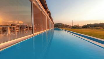Una piscina con cerramiento de vidrio, vista del paisaje y cielo despejado.