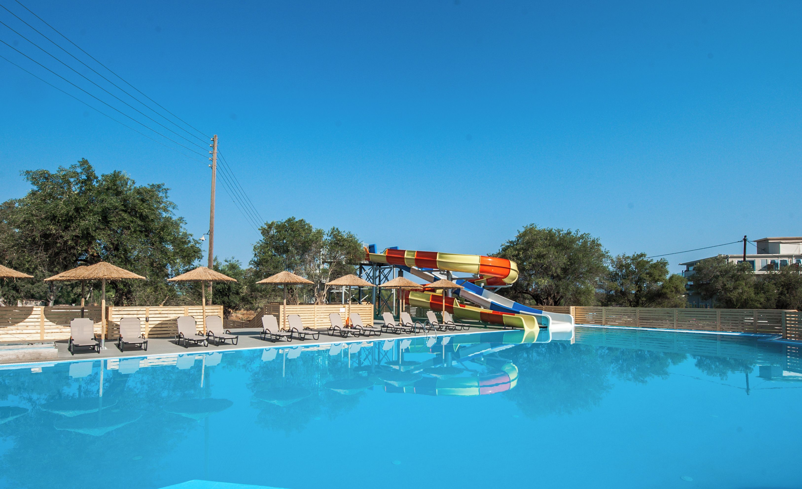 A swimming pool with a water slide, lounge chairs, and umbrellas.