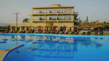 Un hotel con piscina, sillas de descanso y sombrillas.