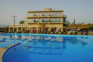 A hotel with a swimming pool, lounge chairs, and umbrellas. - Laguna Holiday Resort Corfu (Corfu)