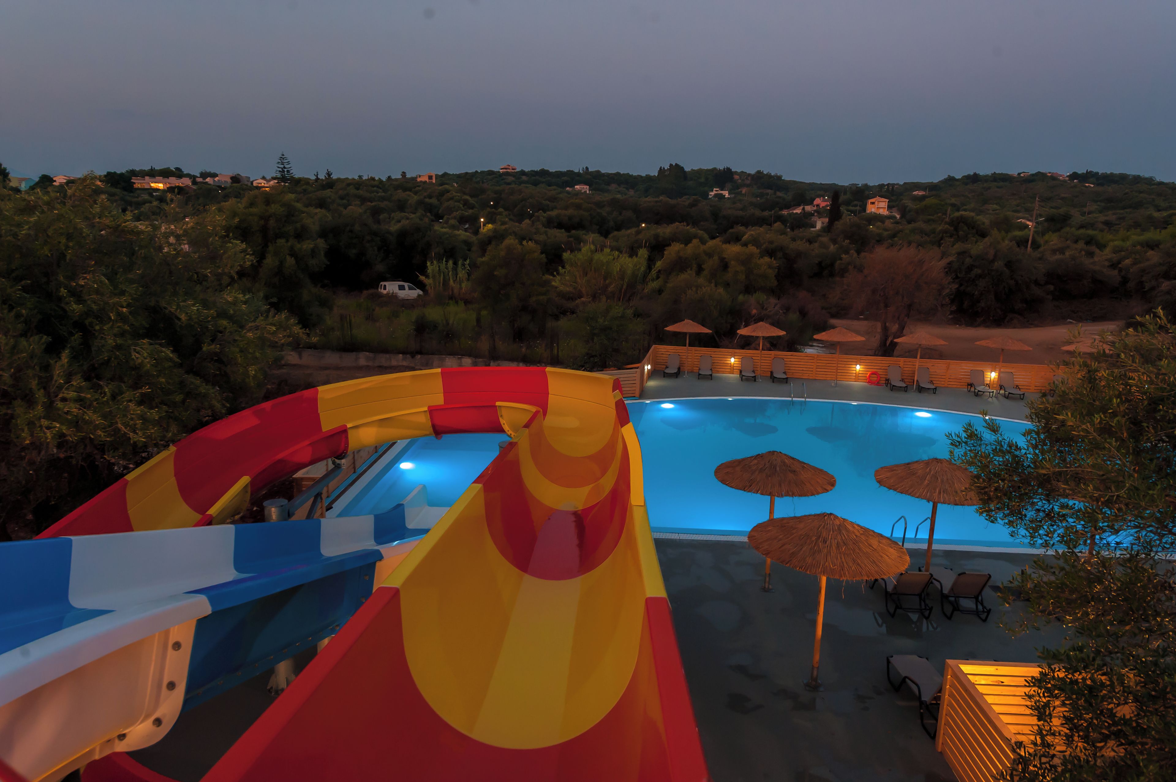 A water slide leading to a pool with lounge chairs and umbrellas.