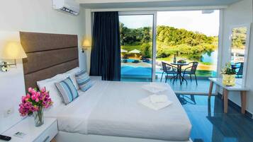 Habitación de hotel con cama, mesita de noche, lámpara, un jarrón de flores y vistas a una piscina y zona de estar exterior.