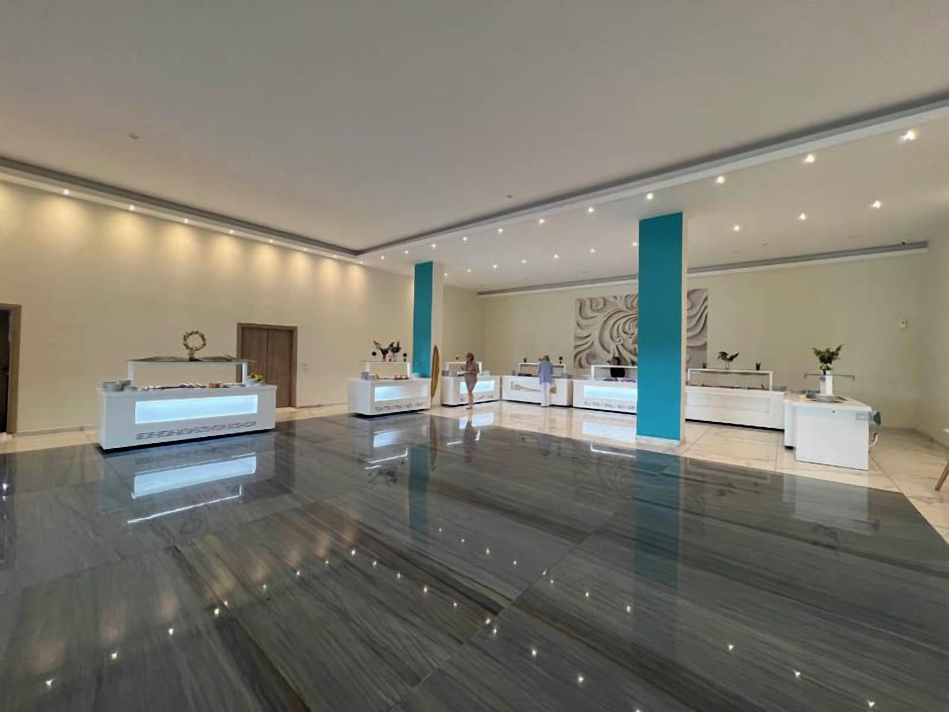 Eine geräumige Lobby mit glänzendem Marmorboden, mehreren Rezeptionstheken und einem großen Wandbild.