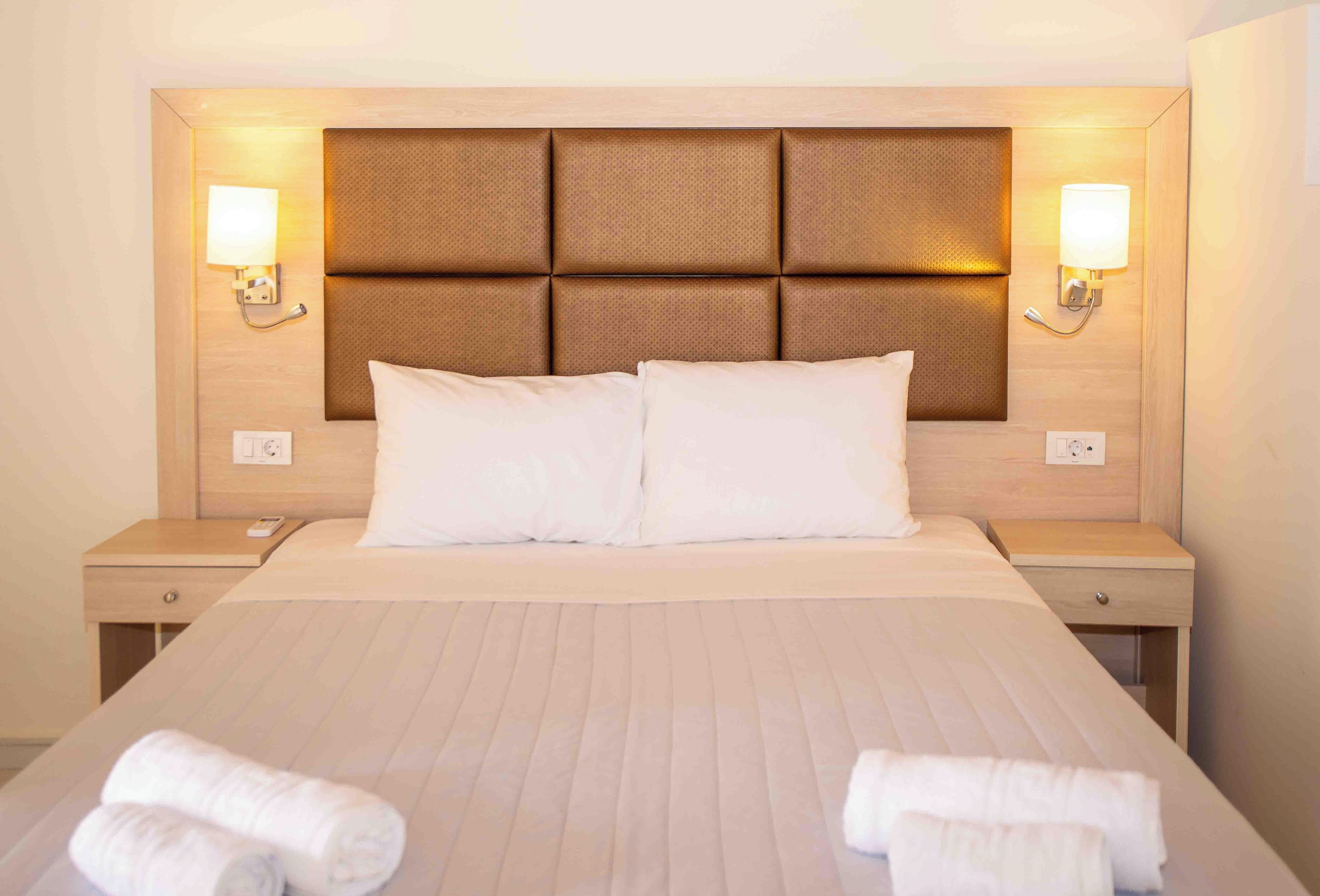 Una habitación de hotel con una cama grande, dos mesitas de noche y lámparas fijadas a la pared.