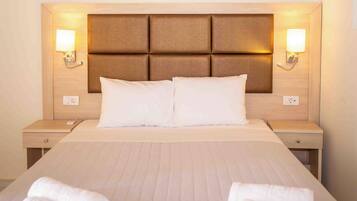 Una habitación de hotel con una cama grande, dos mesitas de noche y lámparas fijadas a la pared.