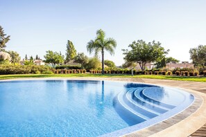 A clear swimming pool with a tiled edge, surrounded by a wooden deck and greenery. - Lumina Villas (Lagoa)