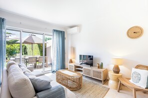 Uma sala de estar moderna com sofá, televisão e área de jantar com cadeiras e mesa.