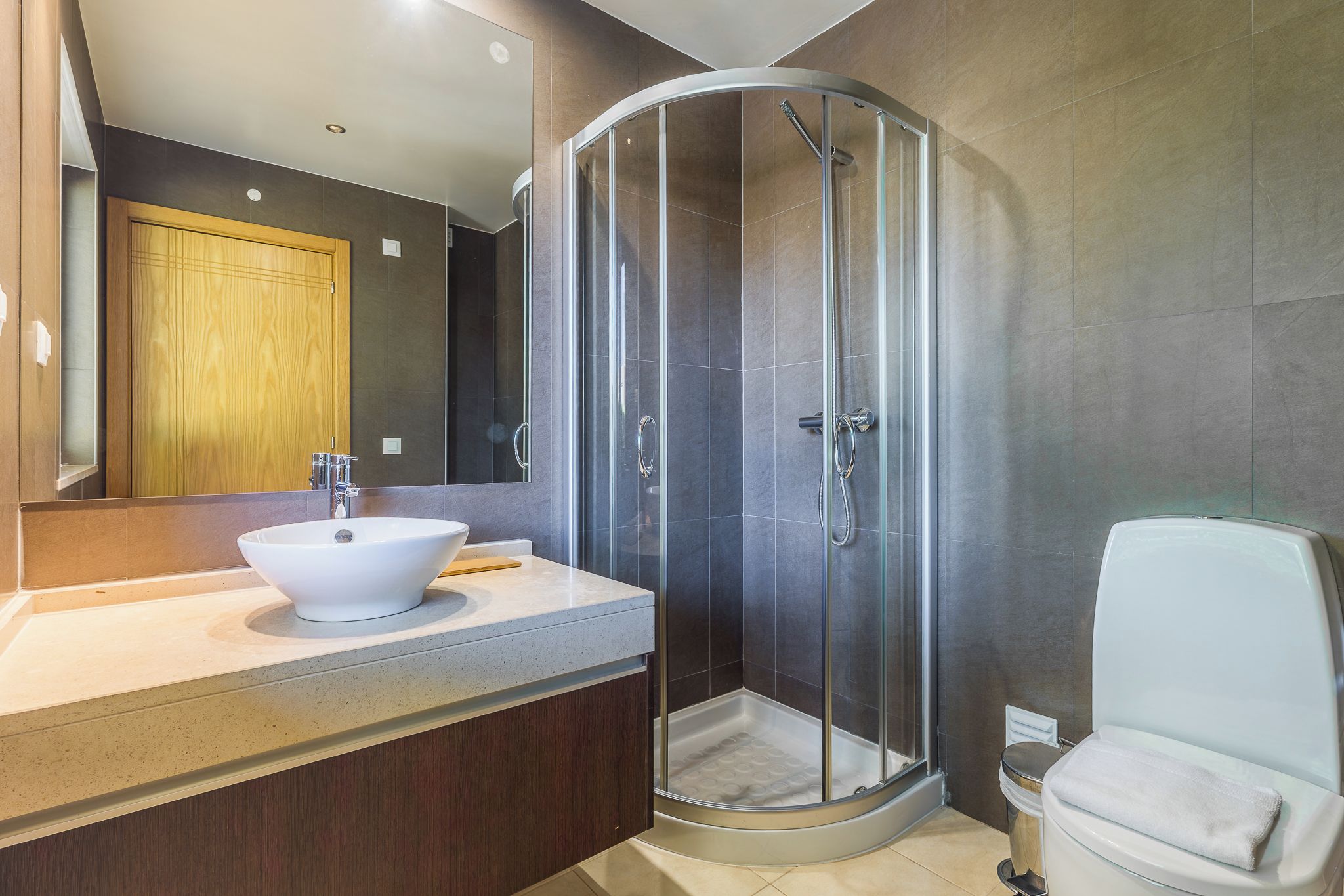 Une salle de bain moderne avec une douche à parois incurvées, un lavabo blanc et des toilettes.