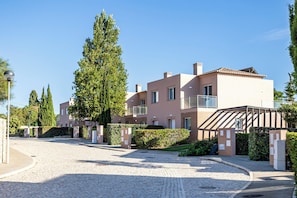 A modern residential building with a paved driveway, a covered outdoor area, and a well-maintained garden. - Lumina Villas (Lagoa)