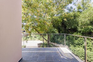 A balcony with a metal railing, a tiled floor, and a view of trees and greenery. - Lumina Villas (Lagoa)
