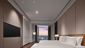 A modern hotel room with a large bed, a flat-screen TV, a city view, and a wooden floor. - Wanda Realm Yudu Ganzhou (Guangzhou)