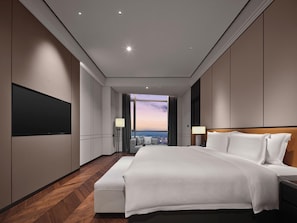 Una habitación de hotel moderna con una cama grande, televisión de pantalla plana, vista a la ciudad y piso de madera.