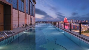 A rooftop infinity pool with a city view, modern architecture, and a red bridge in the background. - Wanda Realm Yudu Ganzhou (Guangzhou)