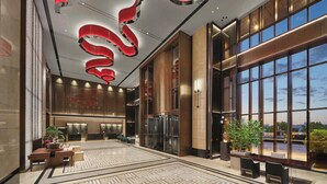 A spacious lobby with a modern design, featuring a large reception desk, seating area, and large windows offering a view of the cityscape. - Wanda Realm Yudu Ganzhou (Guangzhou)