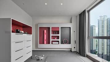 A modern room with a large window, a workout mat, and a wardrobe with red accents.