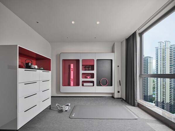 Una habitación moderna con un ventanal grande, una colchoneta de ejercicios y un armario con detalles rojos.