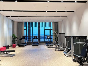Un gimnasio moderno con cintas de correr, máquinas de pesas y un amplio ventanal con vistas a la ciudad.