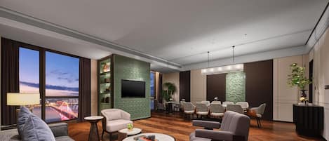 A modern living room with a large TV, comfortable seating, a dining area, and a view of a cityscape.