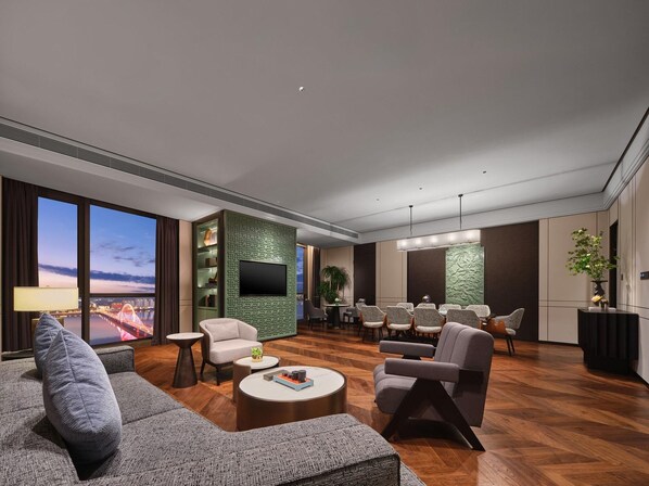 Una sala de estar moderna con un televisor grande, asientos cómodos, un comedor y vistas de la ciudad.