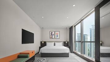 Una habitación de hotel moderna con una cama grande, televisión, obras de arte, balcón con vistas a la ciudad y equipo de ejercicio.