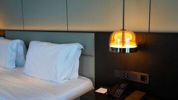 Una habitación de hotel con cama, una mesita de noche con control remoto y una lámpara de pared.