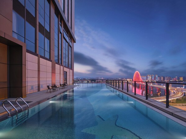 A rooftop infinity pool with a city view, modern architecture, and a red bridge in the background. - Wanda Realm Yudu Ganzhou (Guangzhou)