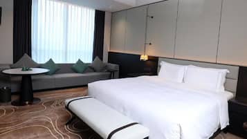 A hotel room with a bed, a bench, a sofa, a small table, and a lamp.