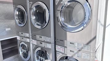 Une rangée de quatre sèche-linge professionnels LG, dotés d’une finition en acier inoxydable, chacun muni d’un écran numérique et d’un panneau de commande.