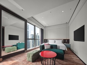A modern hotel room with a large window, a bed, a TV, and a red table. - Wanda Realm Yudu Ganzhou (Guangzhou)