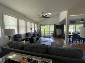 Ein geräumiges Wohnzimmer mit einer großen Couch, einem Esstisch und einem Deckenventilator.