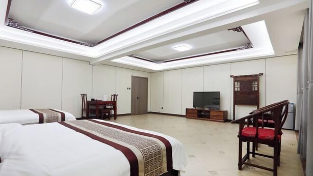 Quarto de hotel com uma cama grande, televisão, escrivaninha e uma cadeira.