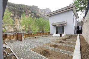 A traditional building with a tiled roof and a paved courtyard with raised garden beds. - Guishanju Boutique Homestay (Laishui)