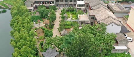 A traditional building with multiple roofs, surrounded by lush greenery and a river.