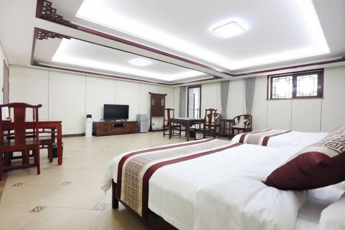 Quarto de hotel com cama, televisão, secretária e cadeira.