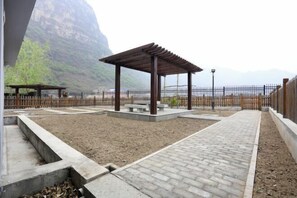 A park with a wooden pergola, concrete benches, and a paved walkway. - Guishanju Boutique Homestay (Laishui)