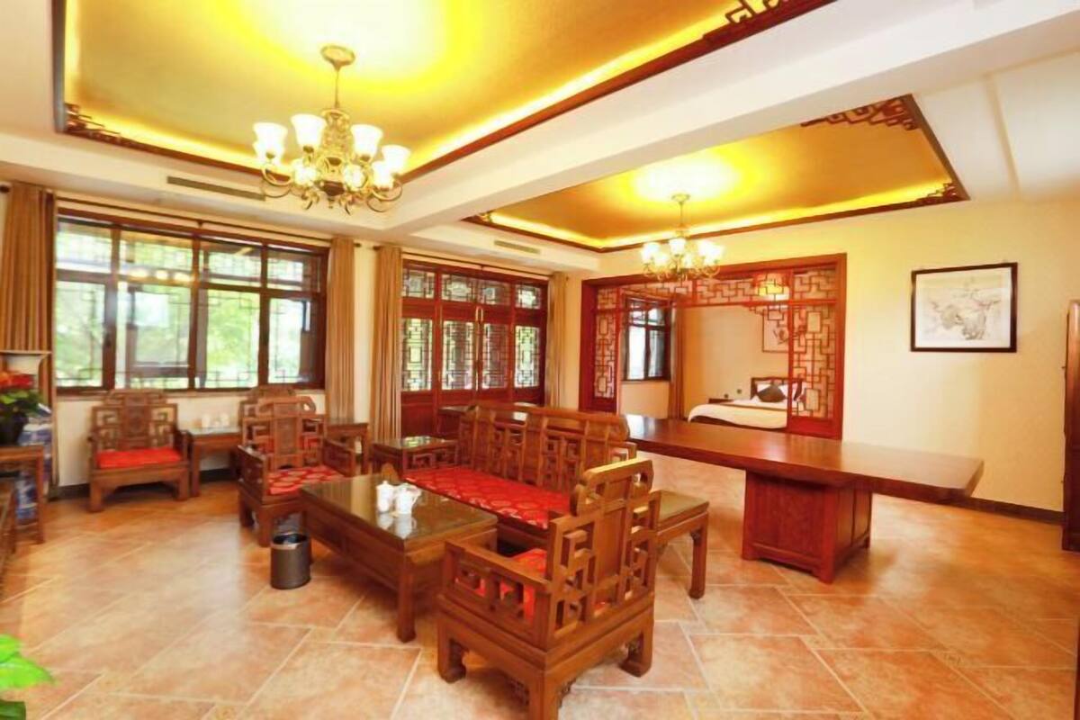 Uma sala de jantar de estilo tradicional com mobiliário de madeira, janelas amplas e painéis decorativos nas paredes.