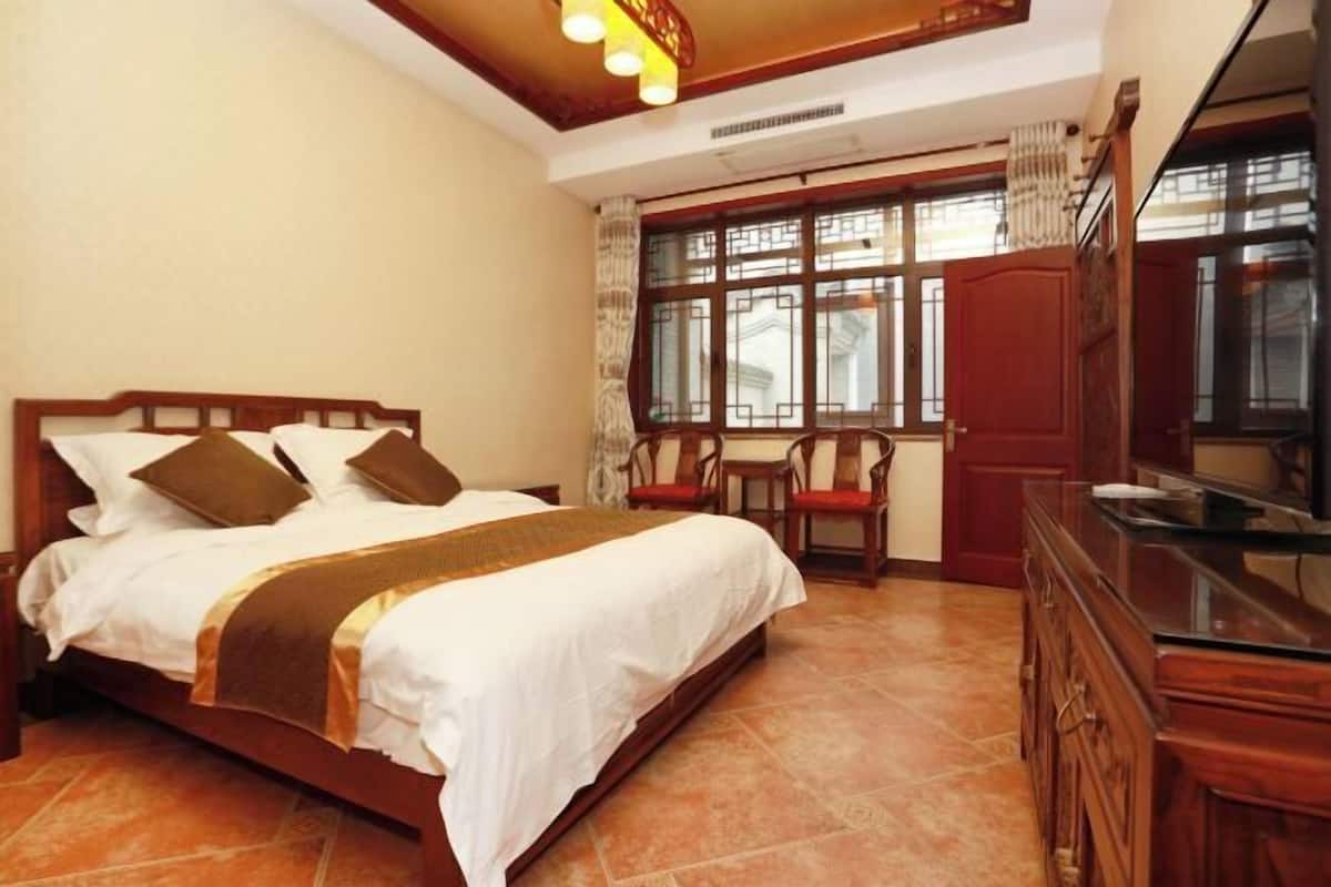 Quarto com cama, cadeiras, armário e janela com vista.