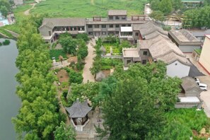 A traditional building with multiple roofs, a central courtyard, and a small pavilion. - Guishanju Boutique Homestay (Laishui)