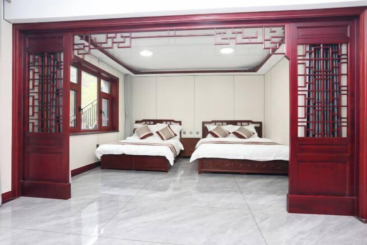 Quarto com duas camas, uma janela e uma porta com design tradicional.